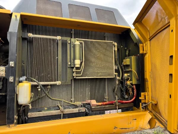 Engine bay open — coolers, batteries, and hydraulic lines